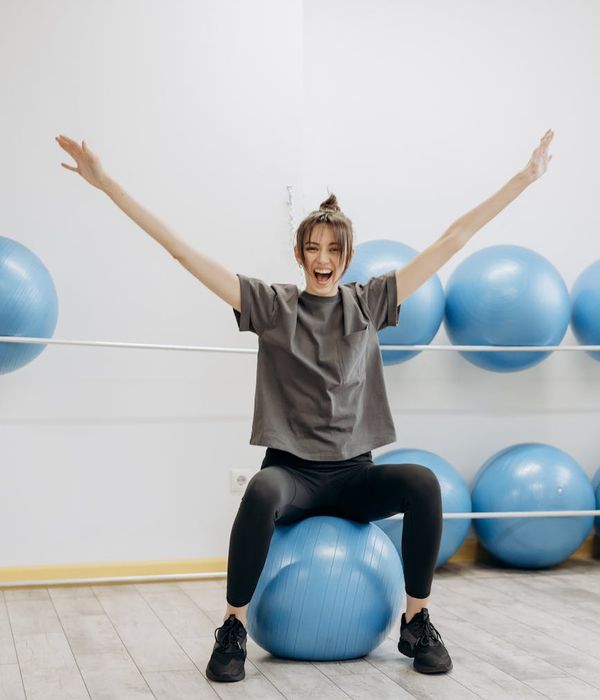 Smiling woman stretching in a bright, sunlit room, feeling energetic.